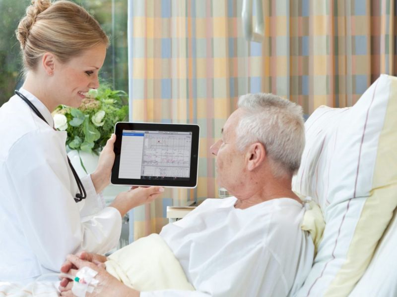 Sykepleier viser pasient journal på nettbrett