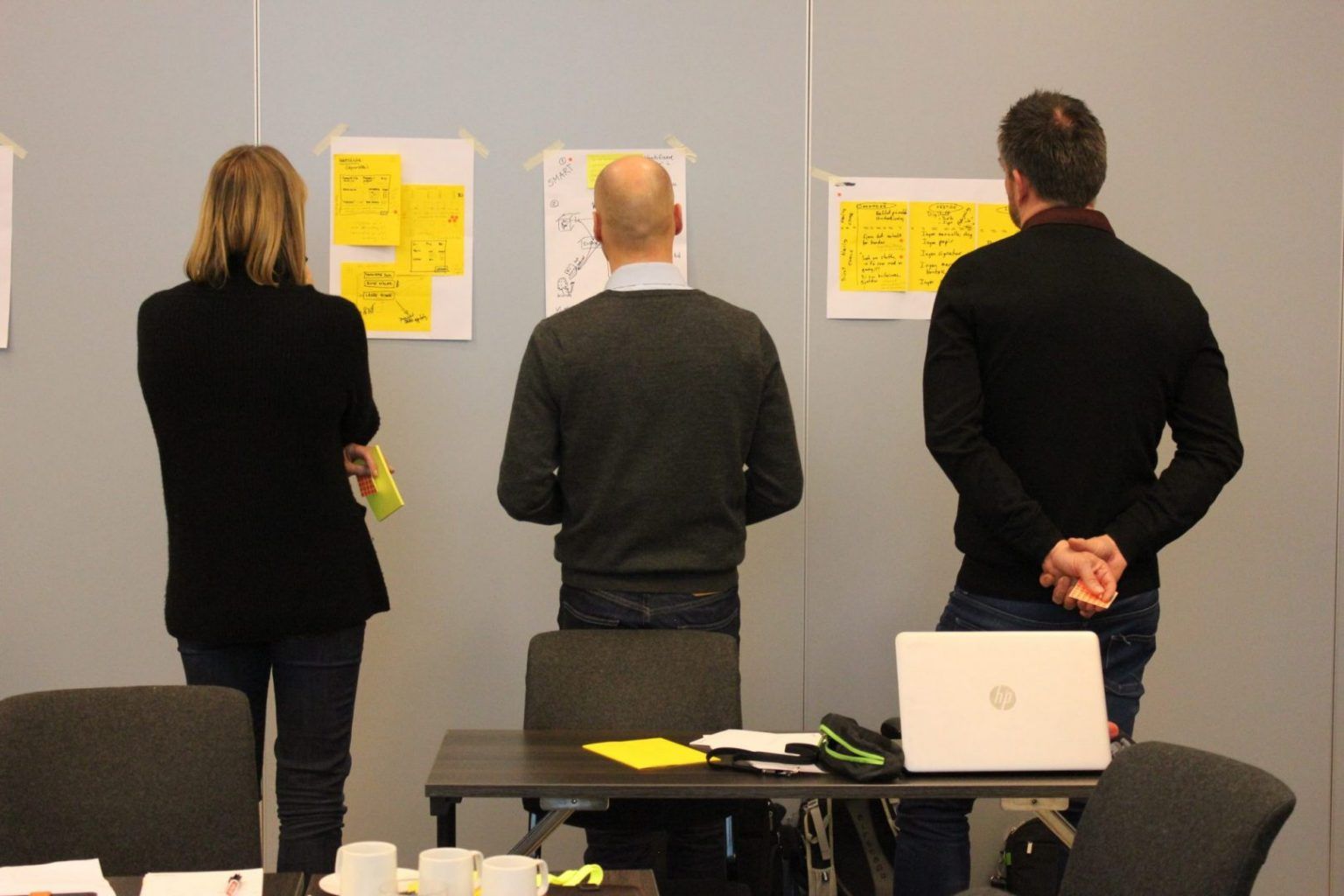Tre personer foran en vegg i en workshop