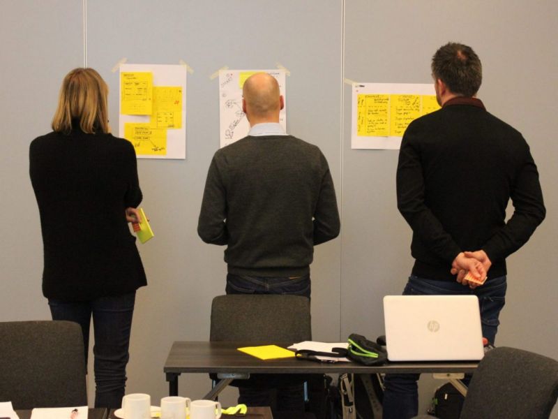 Tre personer foran en vegg i en workshop