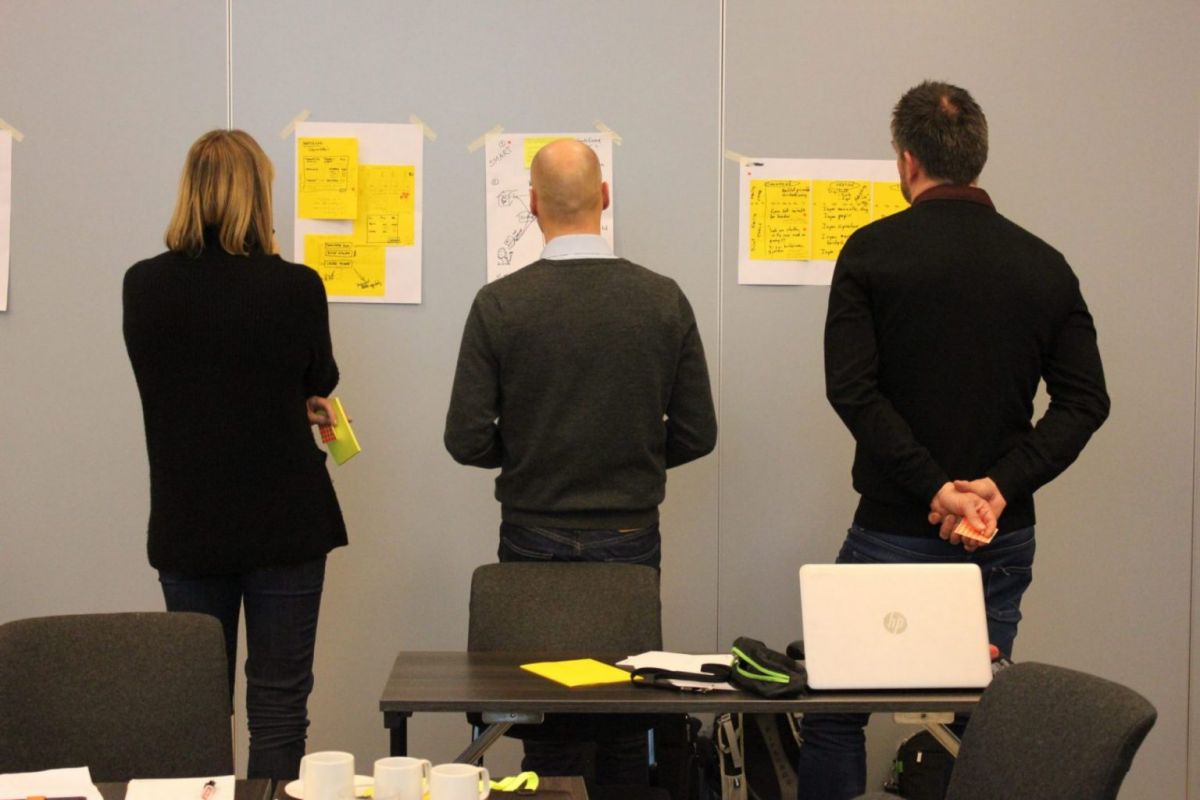 Tre personer foran en vegg i en workshop