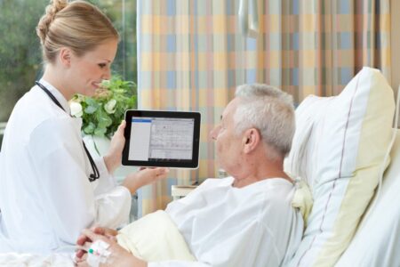 Sykepleier viser pasient journal på nettbrett